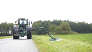 Kättingröjare HCM-1700 klipper gräs längs vägen, bakifrån