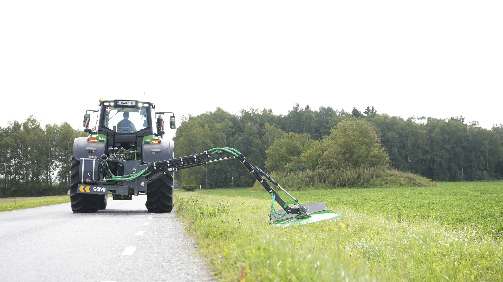 Kättingröjare HCM-1700 klipper gräs längs vägen, bakifrån