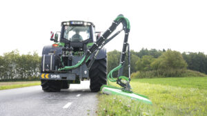 Kättingröjare HCM-1700 klipper vägrenen bakom traktorn